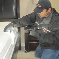 Bed bug inspection technician checking a mattress and bed frame for signs of infestation in Fort Lauderdale, FL