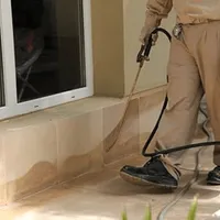 General pest control technician spraying exterior perimeter around a home in Fort Lauderdale, FL