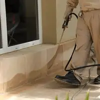General pest control technician spraying exterior perimeter around a home in Fort Lauderdale, FL