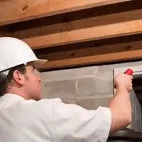 Termite inspection technician checking a basement wall and framing for termite activity in Fort Lauderdale, FL